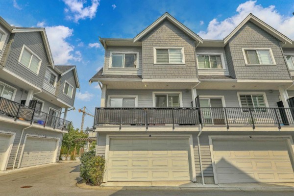 Close-up exterior view of a grey townhouse with multiple floors and garages. - 37 12830 62 Avenue, Surrey