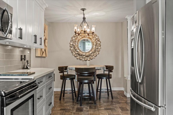 Kitchen island with bar stools and a decorative mirror hangs on the wall. - 37 2525 Yale Court, Abbotsford