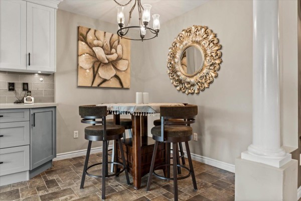Dining area with a table, bar stools, artwork, and a decorative mirror on the wall. - 37 2525 Yale Court, Abbotsford