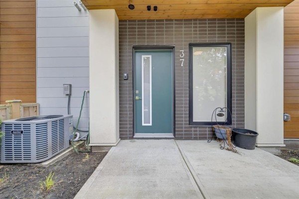 Entryway with a green door, brick detailing, and concrete pathway - 37 5858 132 Street, Surrey