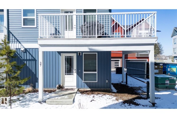 Ground-level entrance to a blue townhouse with a white door and window. - #37 979 Crystallina Nera Wy Nw Nw, Edmonton