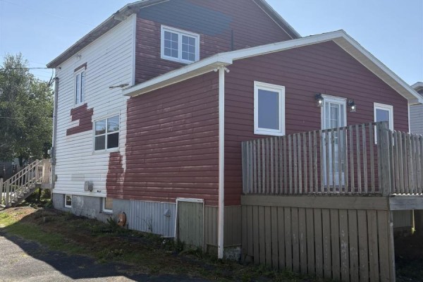 Side view of a two-story house with red and white siding and a wooden deck. - 37 Bennett Street, Grand Lake Road