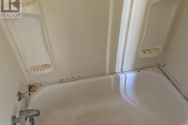 Close-up of a white bathtub with a built-in shower stall and tarnished fixtures. - 37 Bennett Street, Grand Lake Road