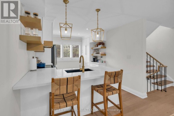 Island kitchen with white quartz countertops, pendant lights, wood flooring, and a view to the living area. - 37 Bowler Street, Aurora