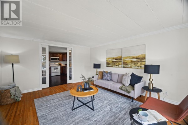 Living room with a view into the kitchen through sliding glass doors, featuring a sofa and chairs. - 37 Cedar Drive, Paradise