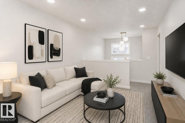 Living room with a large white sectional sofa, coffee table, and mounted television. - 37 Clydesdale Ln, Sherwood Park