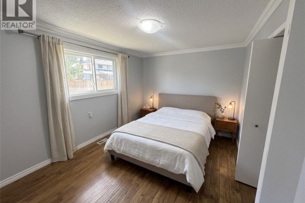 A bedroom with a queen-size bed, neutral bedding, and two bedside tables with modern lamps. - 37 Elora Drive, Hamilton