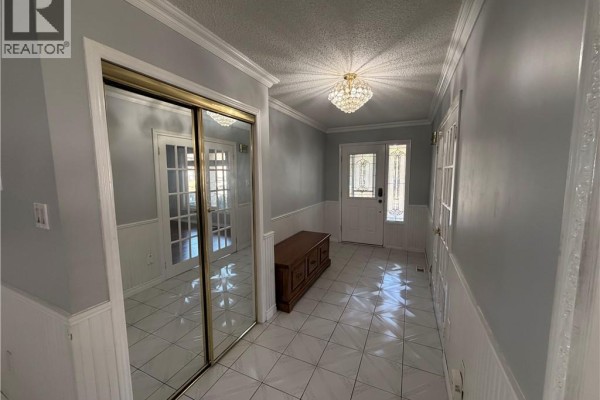 A bright hallway with white wainscoting, mirrored closet doors, and a crystal chandelier on the ceiling. - 37 Elora Drive, Hamilton