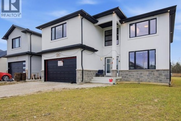 Side view of the house showcasing the stone foundation and landscaped yard. - 37 Kingsbridge Drive, Amherstburg