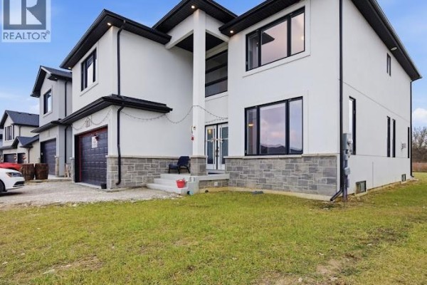 Angle view of the house highlighting the entrance and driveway with grass area. - 37 Kingsbridge Drive, Amherstburg