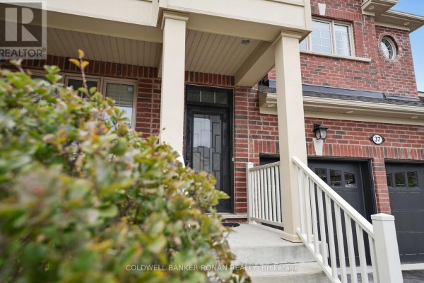 Close-up of the front door entrance with brick facade, porch railing, and decorative plants. - 37 Mcgovern Street, New Tecumseth