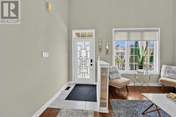 Interior entryway with a glass-paneled front door, light green walls, and two accent chairs. - 37 Mcgovern Street, New Tecumseth