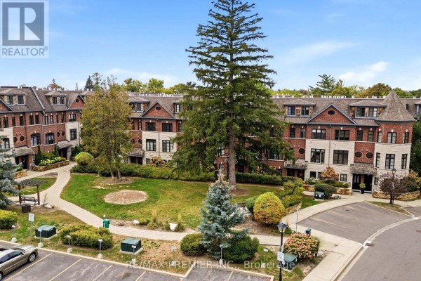 Aerial view of townhouse complex courtyard with paved walkway, grass, trees, and parking area. - 37 Nease Lane E, Vaughan