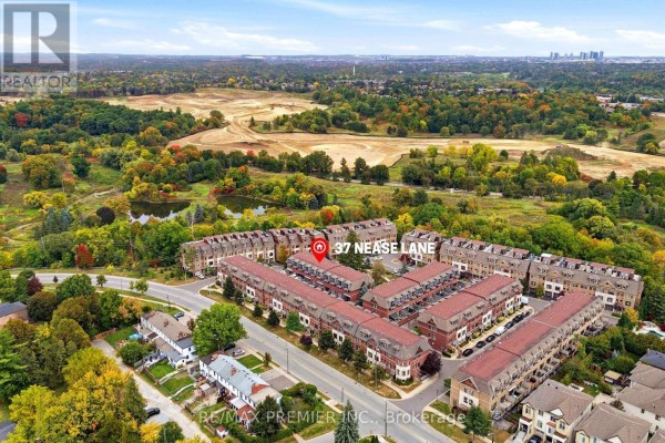 Aerial view of 37 Nease Lane townhouse complex with surrounding green spaces and distant city skyline. - 37 Nease Lane E, Vaughan