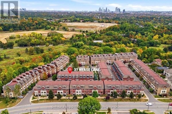 High aerial view of a large townhouse development with surrounding parkland and distant skyscrapers. - 37 Nease Lane E, Vaughan