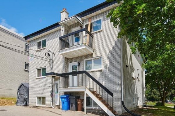Rear exterior of a fourplex building with white brick, black railings, and external staircases. - 37 Rue Lucien-brault, Gatineau