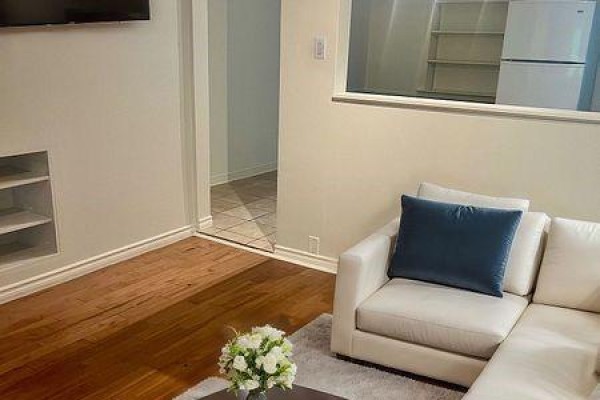 Living room with a white sectional sofa, dark blue cushion, wood floors, and a view into a hallway. - 37 Sellers (main Floor) Avenue, Toronto