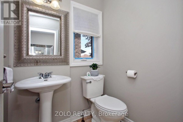 Powder room with a pedestal sink, toilet, and ornate silver mirror above the sink. - 37 Sewells Lane S, Brampton