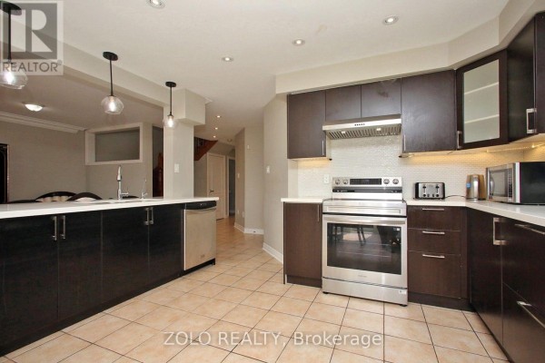 Modern kitchen with dark brown cabinets, stainless steel appliances, and a large island. - 37 Sewells Lane S, Brampton