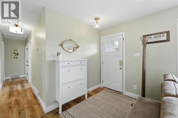 Interior entryway with a white shoe cabinet, mirror, coat rack, and a white front door with a glass inset. - 37 Sherwood Crescent, Red Deer