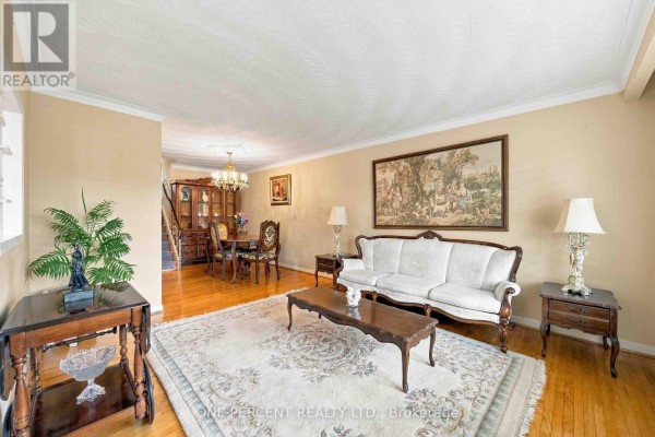 Living room with a white sofa, coffee table, area rug, and dining room in background. - 37 Wilmont Drive, Toronto