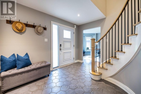 Foyer with a white front door, coat rack with hats, bench with blue cushions, and staircase. - 37 Wyndfield Crescent, Whitby