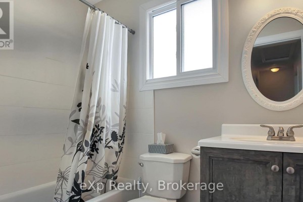 Bathtub, toilet, vanity, and oval mirror in a modern bathroom - 370 6th Avenue Hanover