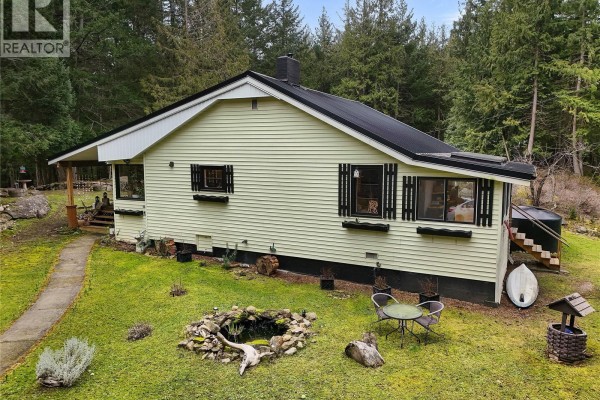 Side view of the house with black shutters and a small pond in the garden. - 370 Campbell Bay Rd, Mayne Island