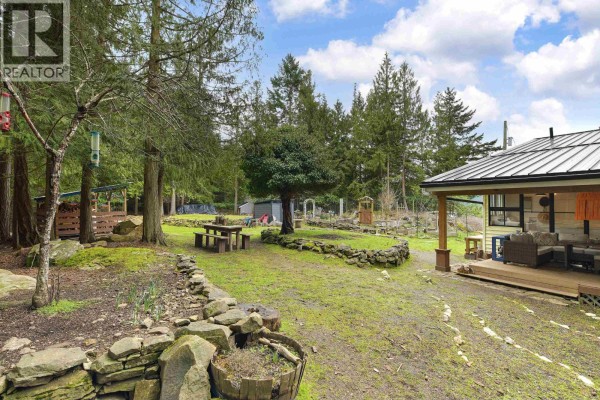 Open yard area with stone borders, picnic table, and view of the house. - 370 Campbell Bay Road, Mayne Island