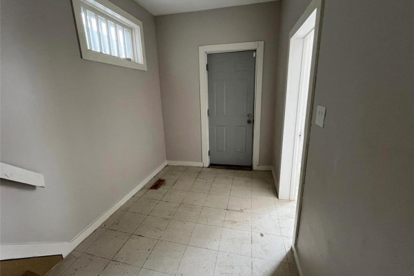 Interior entryway with tiled floor, gray walls, and a gray door leading outside. A small window is above the door. - 370 Pritchard Avenue, Winnipeg