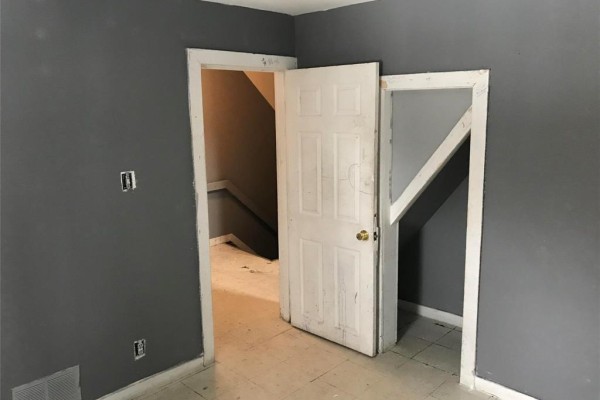 Room with dark gray walls and an open doorway revealing stairs. A white door is ajar in the foreground. - 370 Pritchard Avenue, Winnipeg
