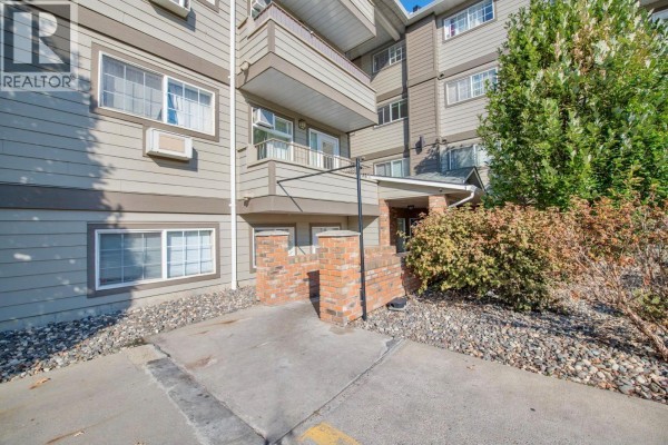 Entrance to the apartment building with brick pillars and beige siding. - 3700 28a Street Unit# 319, Vernon