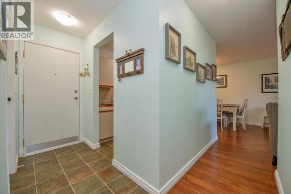 Apartment entryway with light blue walls, decorative frames, and a view into the dining area. - 3700 28a Street Unit# 319, Vernon