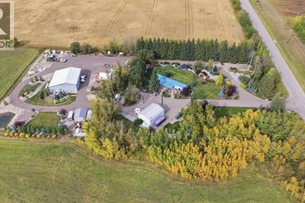 Aerial view of the property showing a blue mobile home, large workshops, and various outbuildings. - 370038 Range Road 4-3, Rural Clearwater County