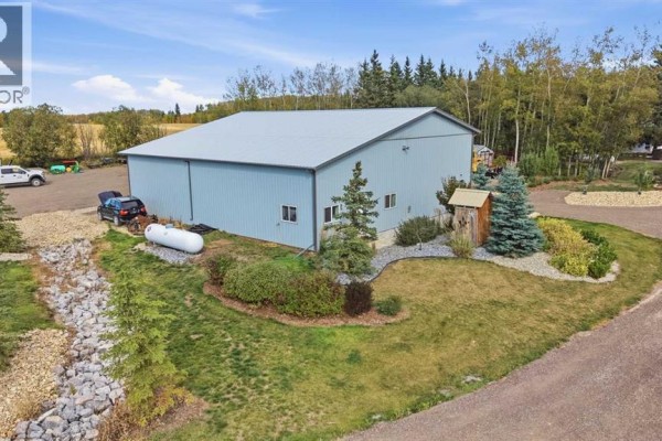 Exterior of a large, light blue metal workshop building with a grey roof and gravel landscaping. - 370038 Range Road 4-3, Rural Clearwater County