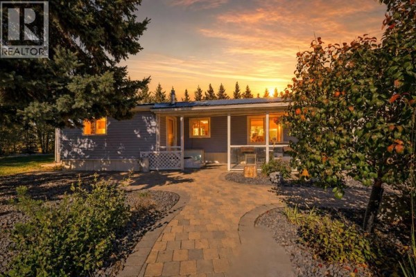 Front of a light blue mobile home with a covered porch and a paved walkway at sunset. - 370038 Range Road 4-3, Rural Clearwater County
