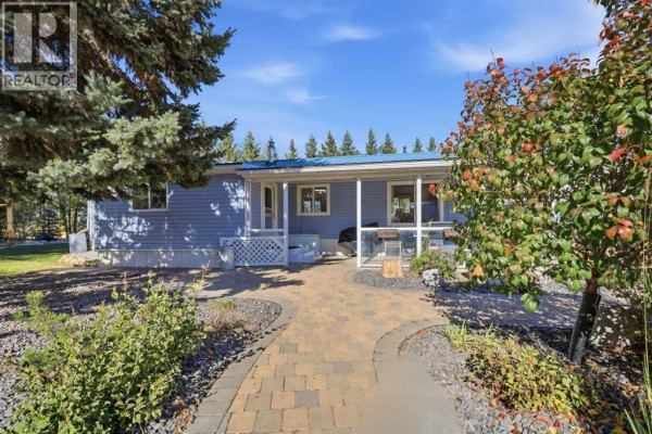 Front of the light blue mobile home with a covered porch and a paved walkway in daylight. - 370038 Range Road 4-3, Rural Clearwater County