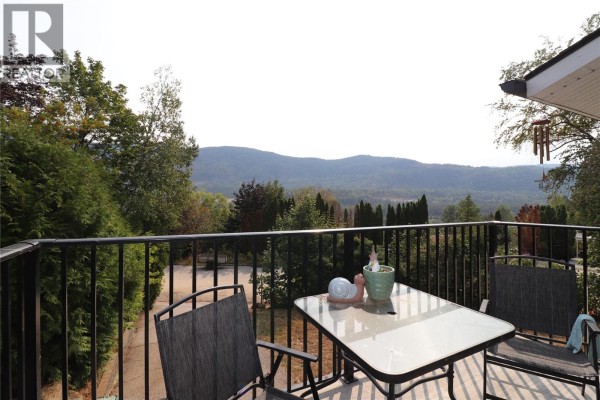 View from deck of mountains and trees with patio furniture. - 3702 9th Avenue, Castlegar