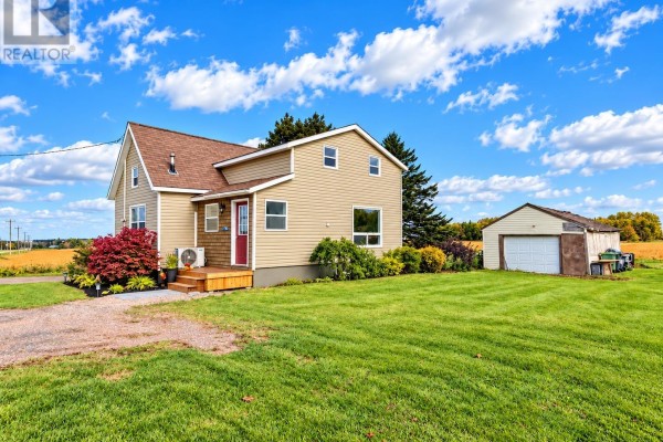 Side exterior view of a two-story beige house with a red front door and a detached garage. - 3702 North Carleton Road, Rte 10, Searletown