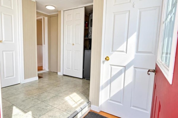Interior view of an entryway with tiled floors, white doors, and a stacked washer and dryer. - 3702 North Carleton Road, Rte 10, Searletown