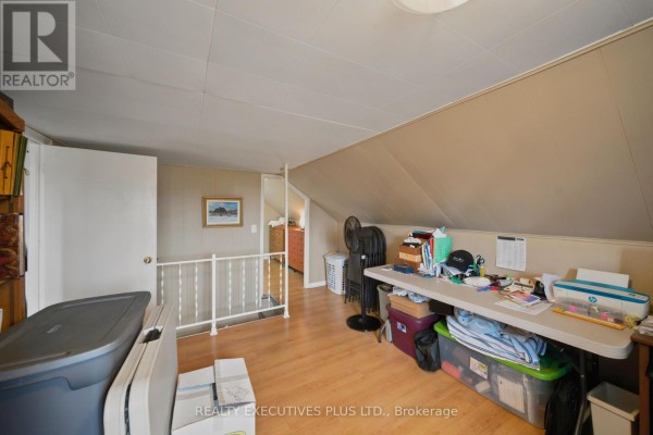 Attic room with sloped ceiling, folding table, printer, fan, and storage - 3705 Champlain Street E Clarence Rockland