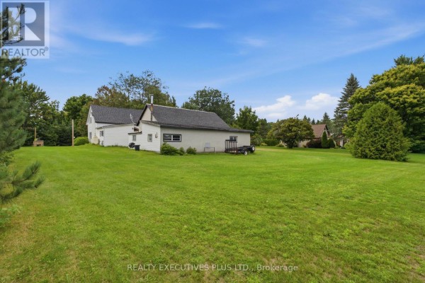 White house with detached garage and trailer on green lawn - 3705 Champlain Street E Clarence Rockland