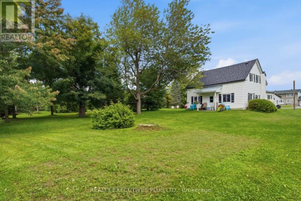 White two-story house with blue chairs on porch - 3705 Champlain Street E Clarence Rockland