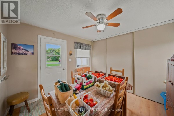 Interior view of a dining area with a table set with produce, wood chairs, and a door leading outside. - 3705 Champlain Street E, Clarence Rockland