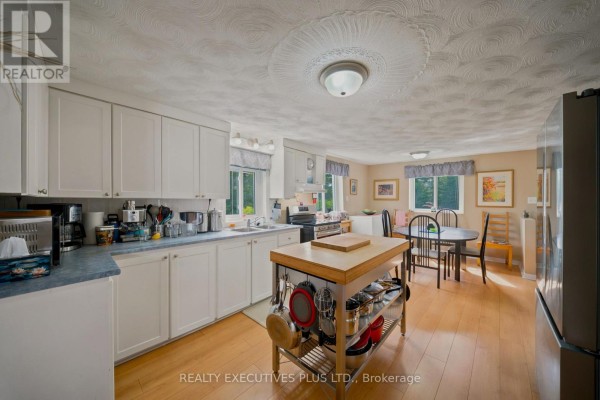 Kitchen and dining area with white cabinets, island, dining table, and wood floors - 3705 Champlain Street E Clarence Rockland
