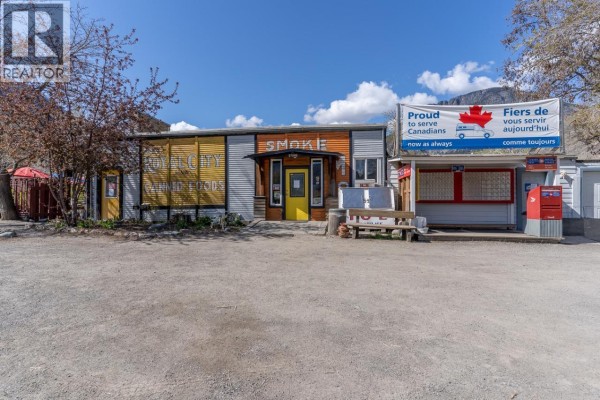Front exterior of a commercial building with multiple storefronts, signs, and outdoor seating. - 3705 Riverview Avenue, Ashcroft