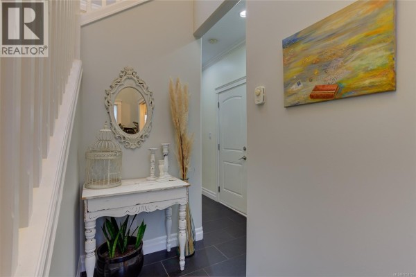Interior view of a hallway with a white console table, ornate mirror, and decorative birdcage. - 3706 Cornus Crt, Langford