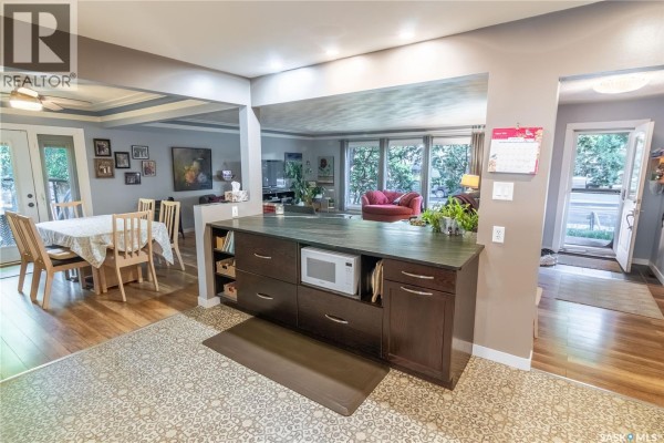 Kitchen island with dark wood cabinets, microwave, and adjoining dining area with a table and chairs. - 3708 Lakeview Avenue, Regina