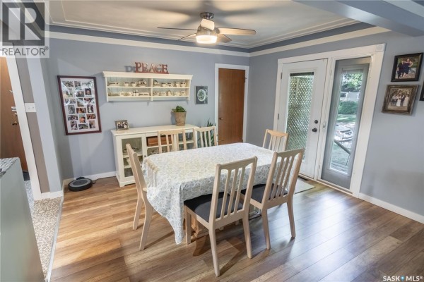 Dining area with a table, chairs, buffet, and glass doors leading to an outdoor space. - 3708 Lakeview Avenue, Regina