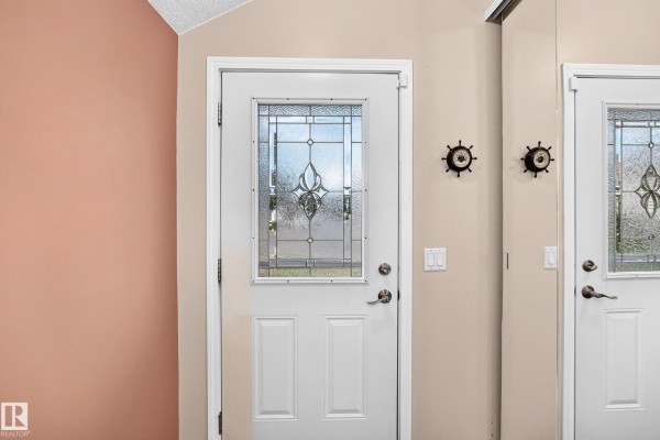 Close-up of a white interior door with a decorative glass panel and silver hardware. - 371 Kirkpatrick Cr Nw, Edmonton
